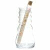 A wavy glass carafe holding a corked, narrow tube filled with colorful crystals, viewed on a white background, resembling an elegant Пръчица за пречистване на вода със скъпоценни камъни "Подреждане и свързване.