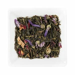 Квадратна бяла чиния, съдържаща смес от изсушени листа от зелен чай и живи цветни листенца, напомнящи за спокойното небе на Синьо Небе.