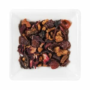 Бяла квадратна купа, пълна с парченца сушени плодове и смес от билки, погледната отгоре, предизвикваща нотка на аромат на Ванилов Крем.