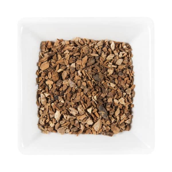 Квадратна бяла чиния, пълна със сушени, нарязани корени или парчета кора, вероятно използвани за билкови или медицински цели, идеално допълва органичния ритуал за смесване на Йога Чай Органик.