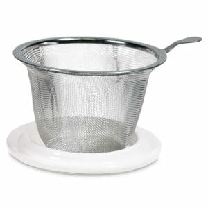 Мрежеста цедка за чай от неръждаема стомана с дръжка, разположена върху бяла пластмасова основа, идеална за накисване на любимите ви смеси в Чаша за чай с цедка Розова Мандала.