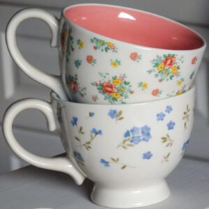 Две Керамични чаши Abby 350 ml с флорални мотиви върху тях стоят върху скрин.